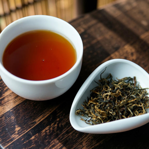 A white ceramic cup filled with amber-brown tea sits on a dark wooden table next to a small white dish holding loose-leaf tea.