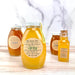 Bottles of 'The North Bee' raw honey on a wooden surface with a blurred background
