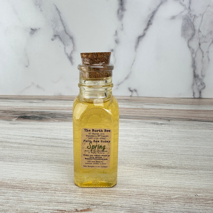 Bottle of honey with cork lid on a marble surface