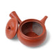 Red ceramic teapot with a lid on a white background